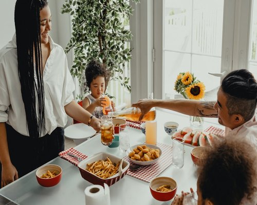 A family passing dishes over a well set dinner table